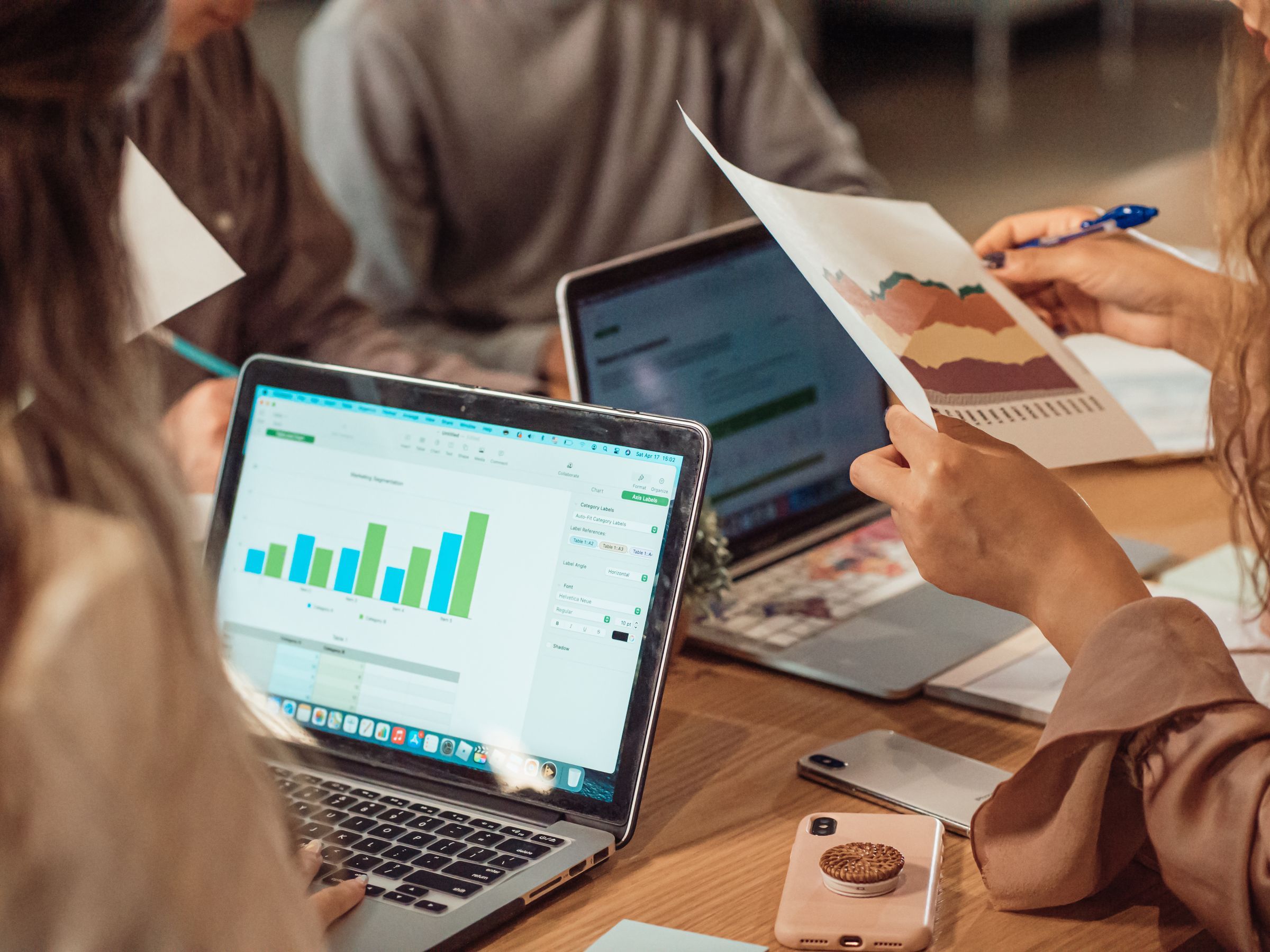 A marketing team reviewing campaign analytics and an integrated media plan around a meeting table